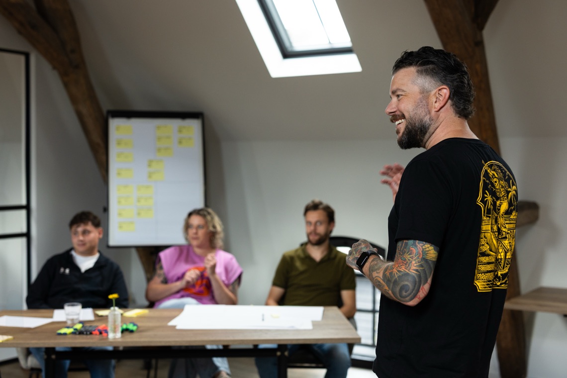 Cas de Morree geeft de training Van Overwerkt naar Overzicht aan een groep deelnemers, met taakbriefjes op een flipover
